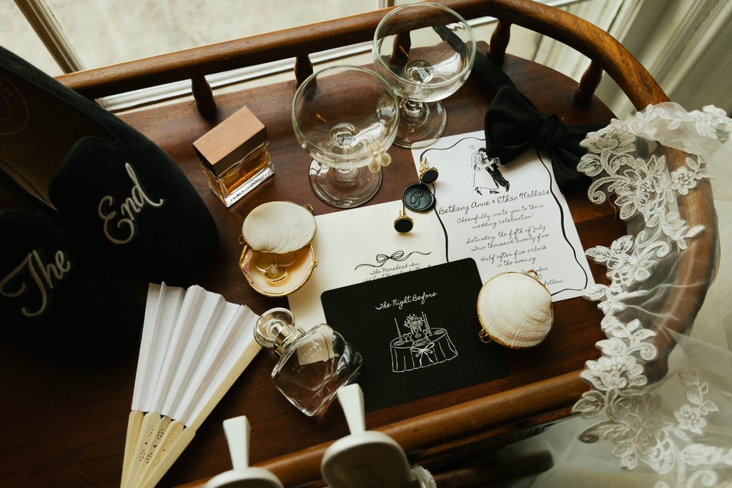 Bethany and Ethan's invitation suite, perfume, fan, and veil styled on an antique chair at The Morehead Inn in Charlotte, NC