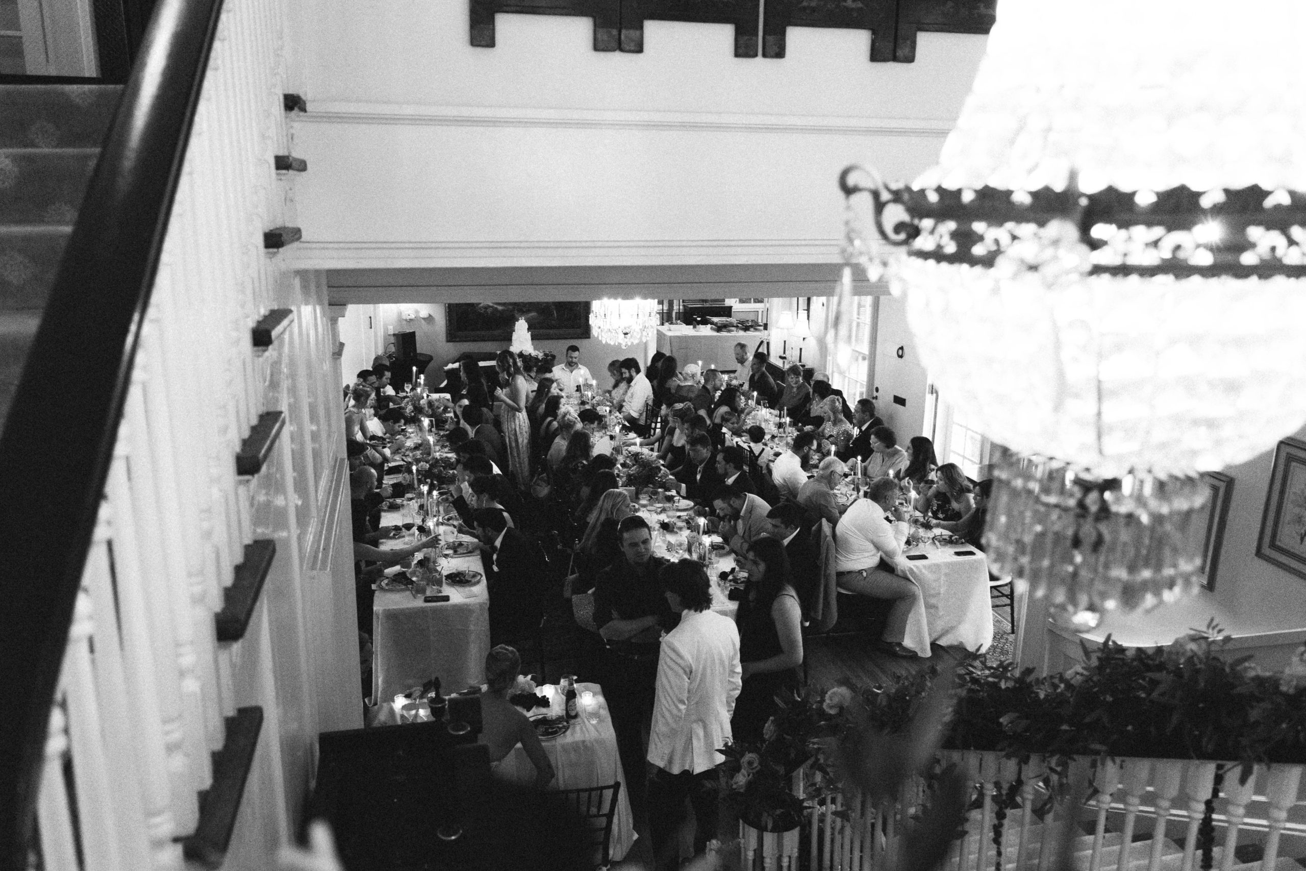 Black and white view from a grand staircase of a candlelit wedding reception at The Morehead Inn in Charlotte