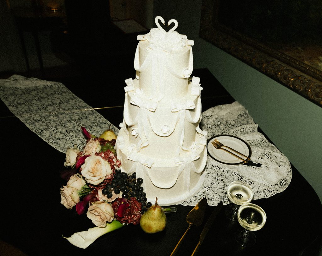 Tiered white wedding cake with lace, moody florals, and pears at Bethany and Ethan's Morehead Inn wedding reception