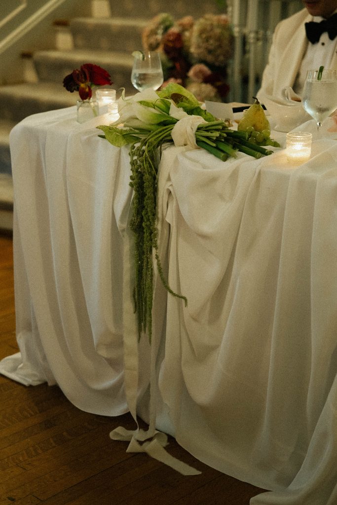 Draped sweetheart table with candles and trailing greenery at Bethany and Ethan's Morehead Inn wedding reception