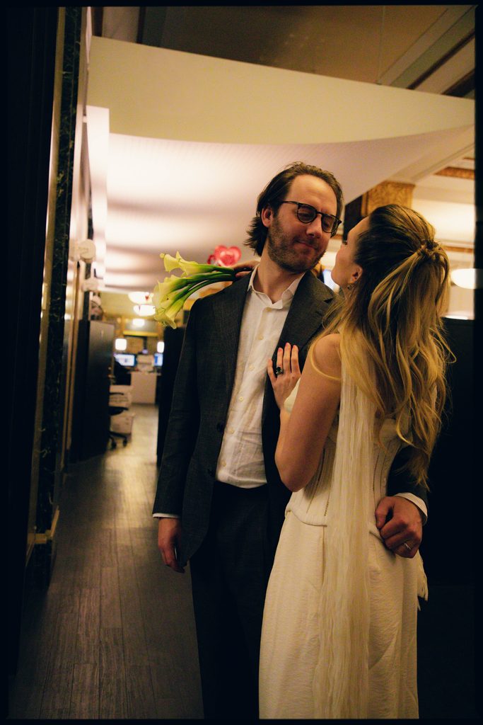 Lauren kissing Jack on the cheek in a warmly lit New York City restaurant hallway