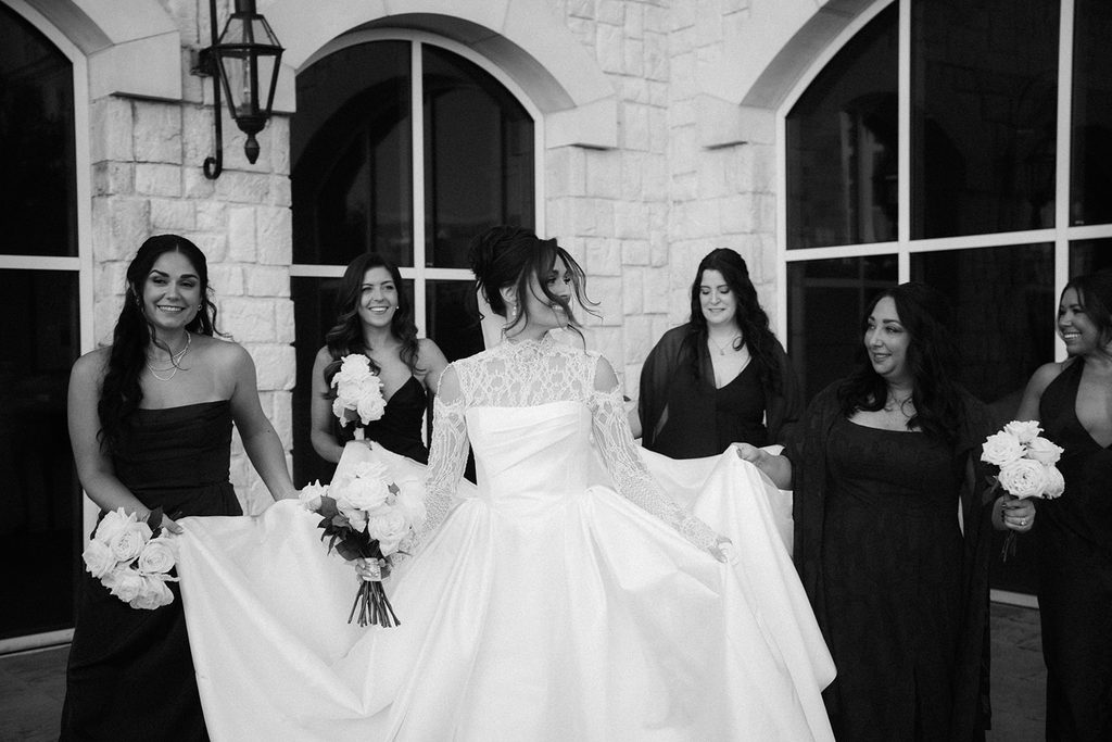 Black and white photo of Marissa and her bridesmaids in black dresses holding white bouquets at The Ballantyne in Charlotte
